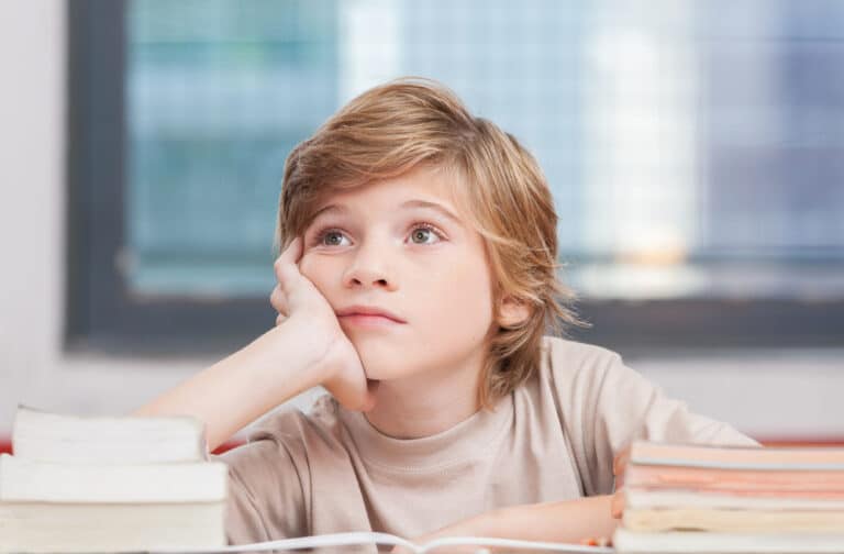 Boy looking off into space while sitting at schooldesk