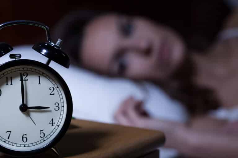 Alarm clock at 3am, woman awake in background
